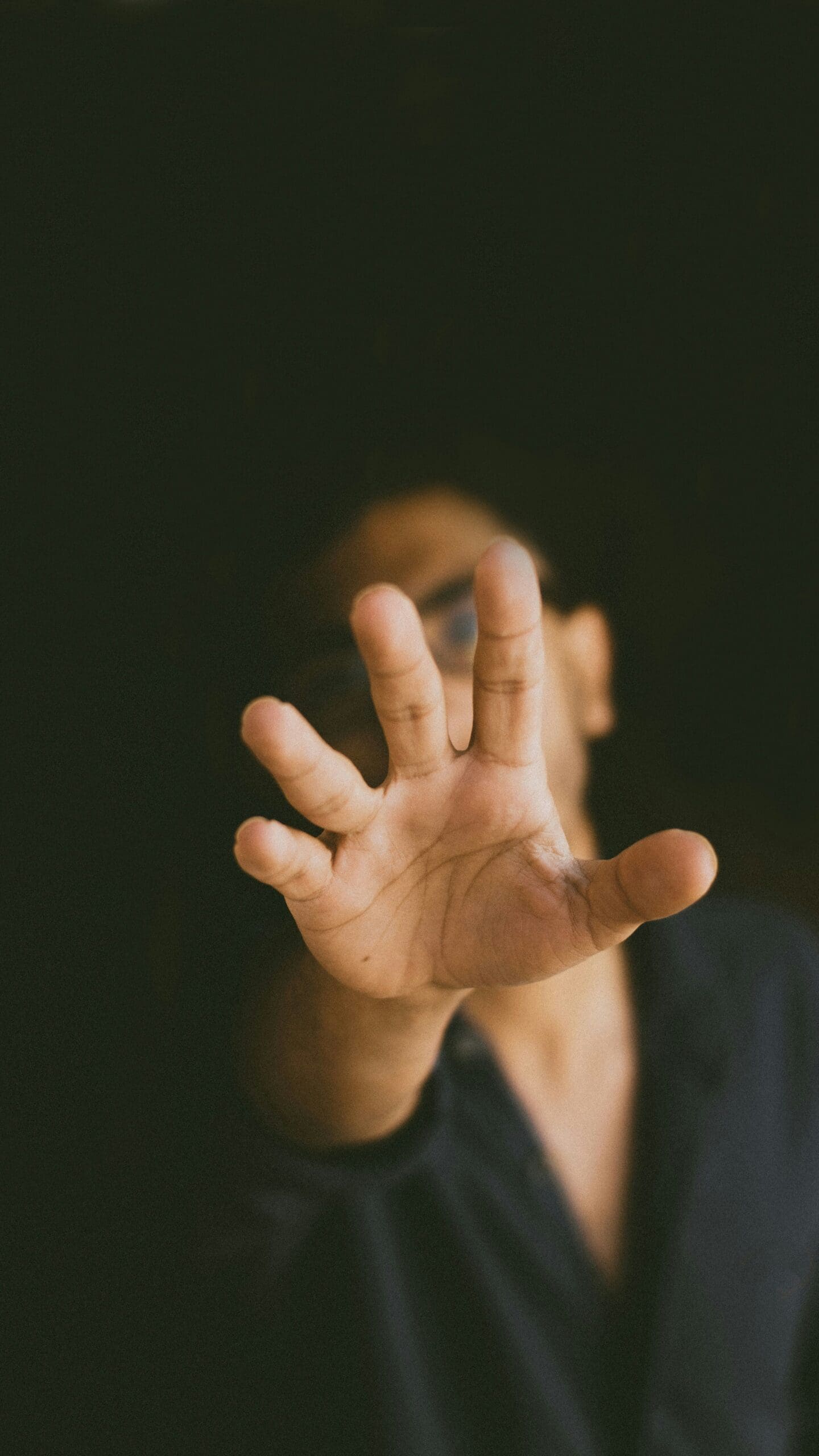 Close-up of an outstretched hand reaching forward from shadow, symbolizing somatic awareness, embodied connection, and healing presence in Nevada.