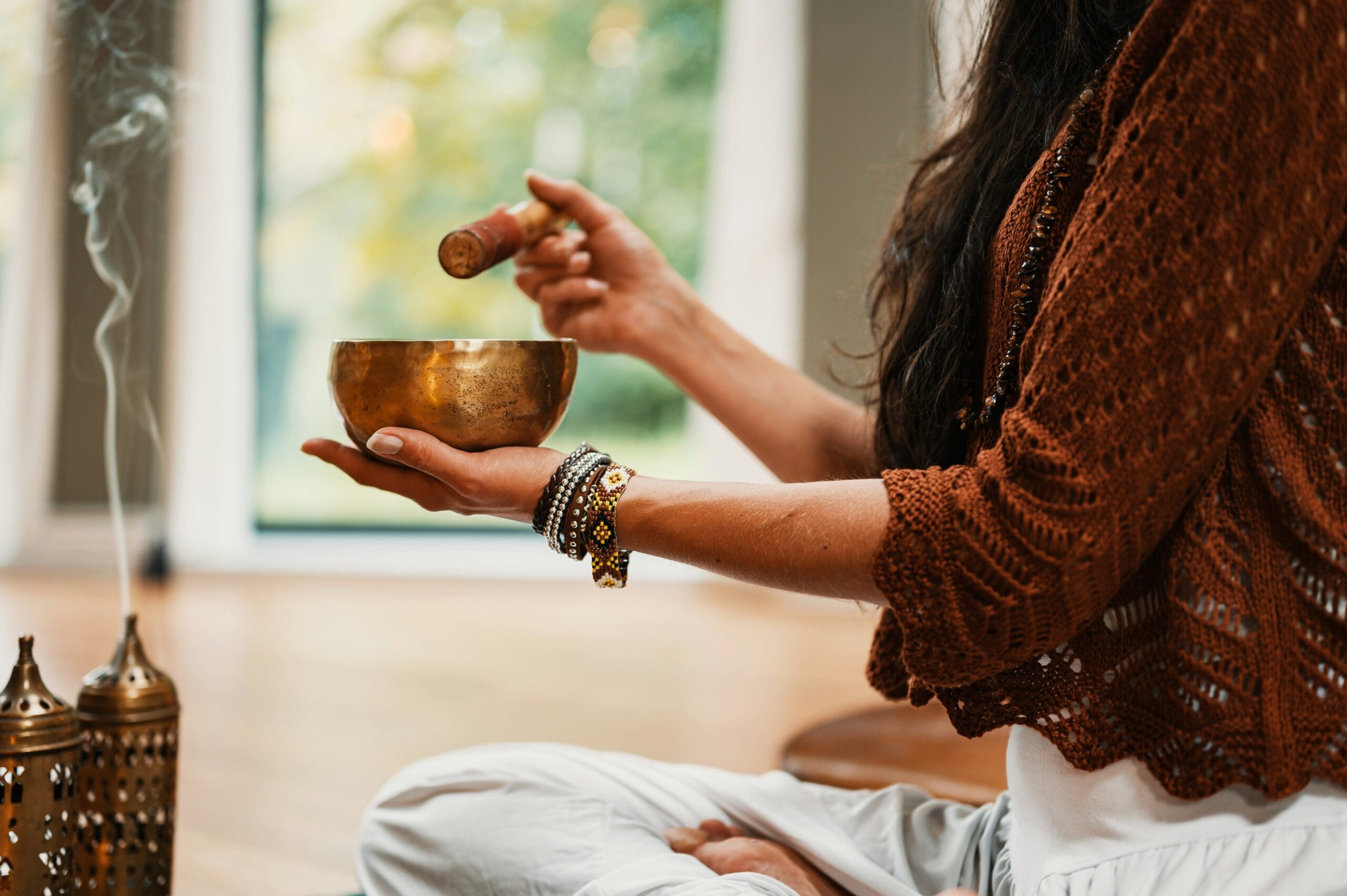 Person holding a singing bowl in soft natural light, with incense smoke rising — symbolizing somatic awareness, mindfulness, and body-based healing practices integrated into Ominira Therapy’s trauma-focused care.