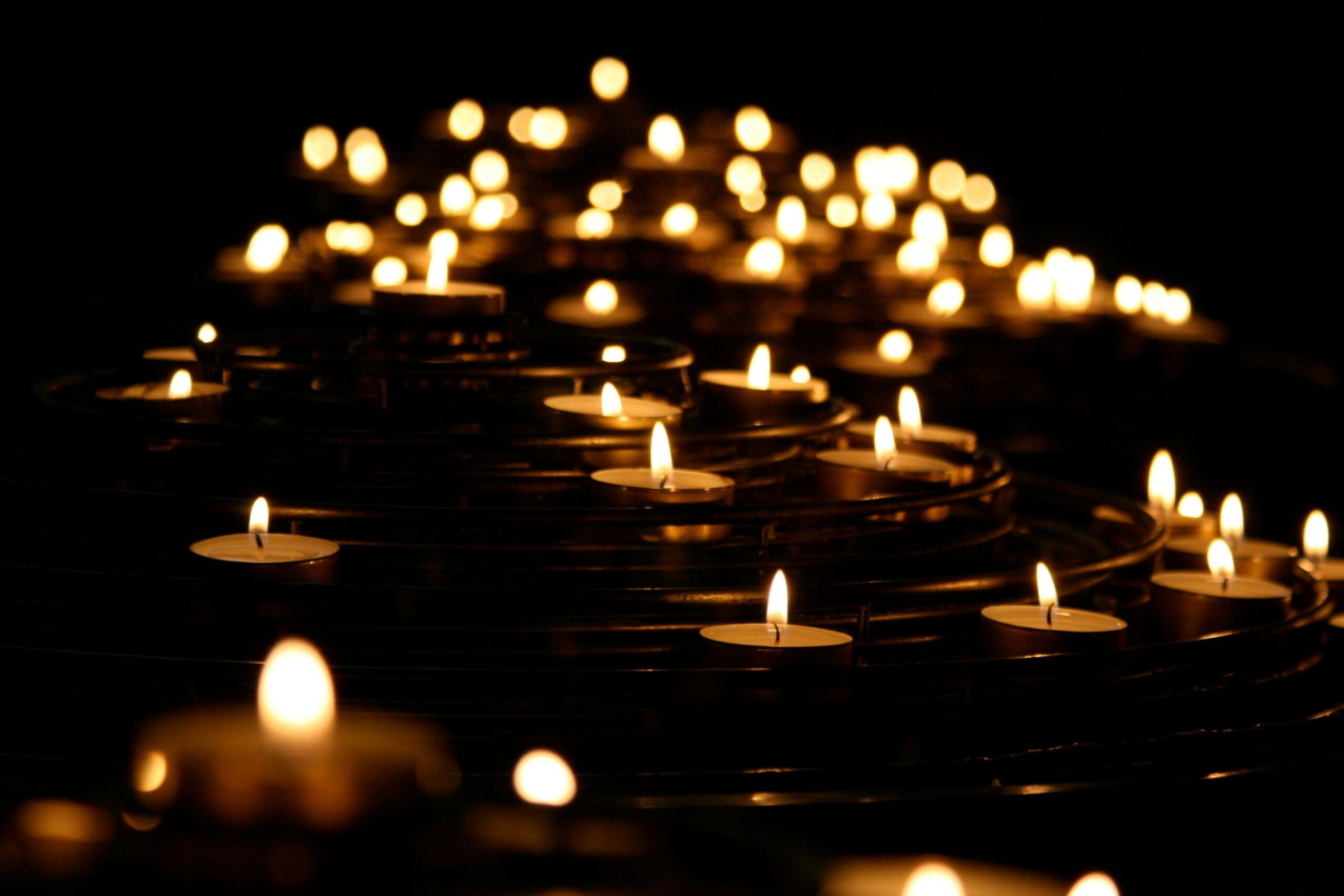 Rows of softly glowing candles in a dark space, symbolizing reflection, healing, and renewal — representing Ominira Therapy’s trauma-informed, somatic approach to emotional well-being in Nevada.