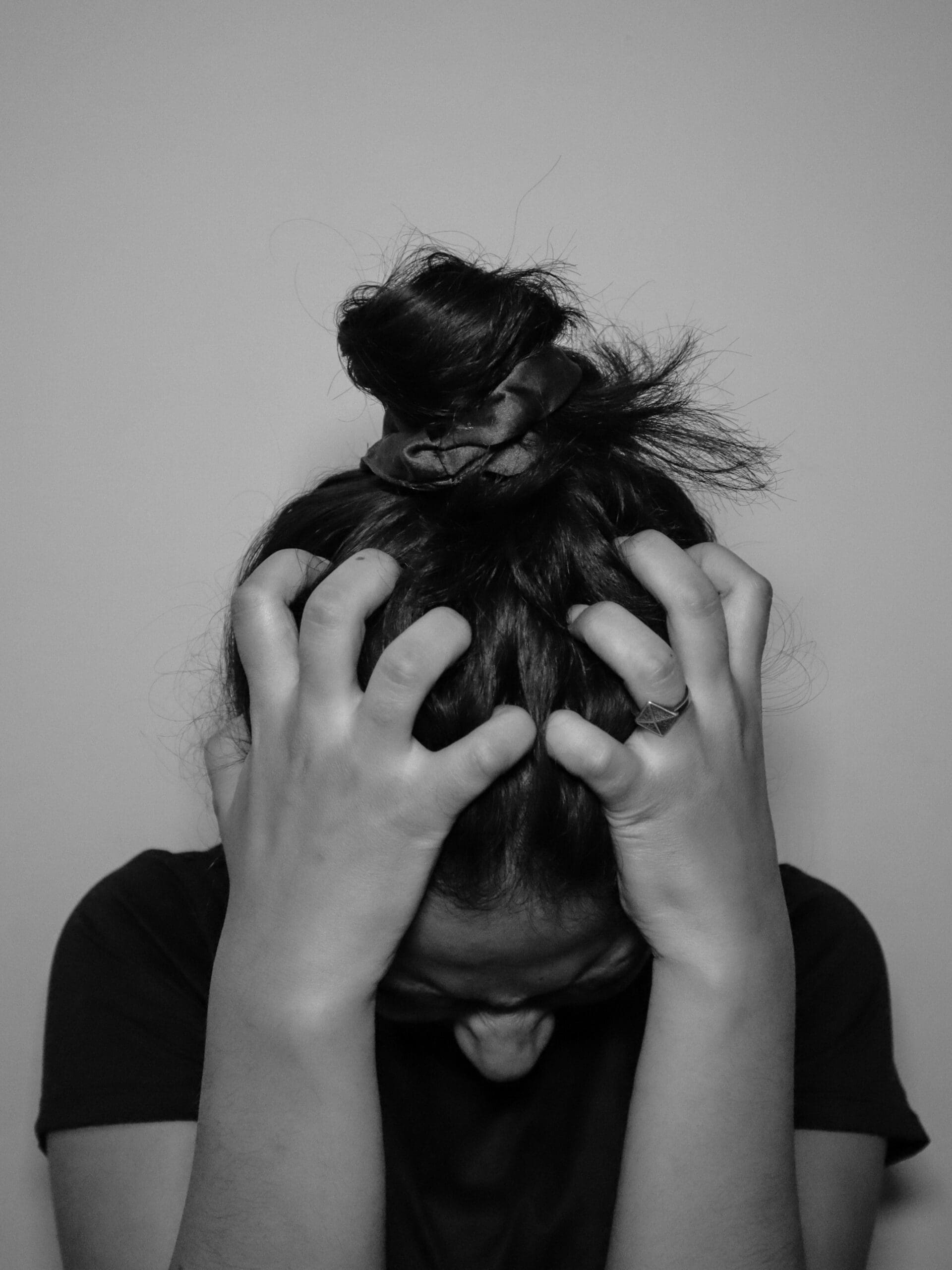 Adult holding neck and shoulders with visible tension, representing physical symptoms of chronic stress, Ominira Therapy Nevada
